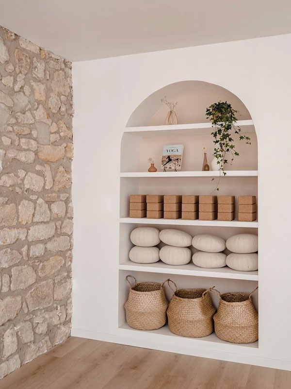 Yoga studio with an arched stone niche and woven baskets by Agathe Corbet