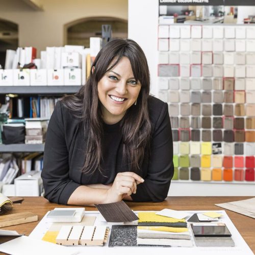 Anna Breheny, interior designer, with a wall of material samples