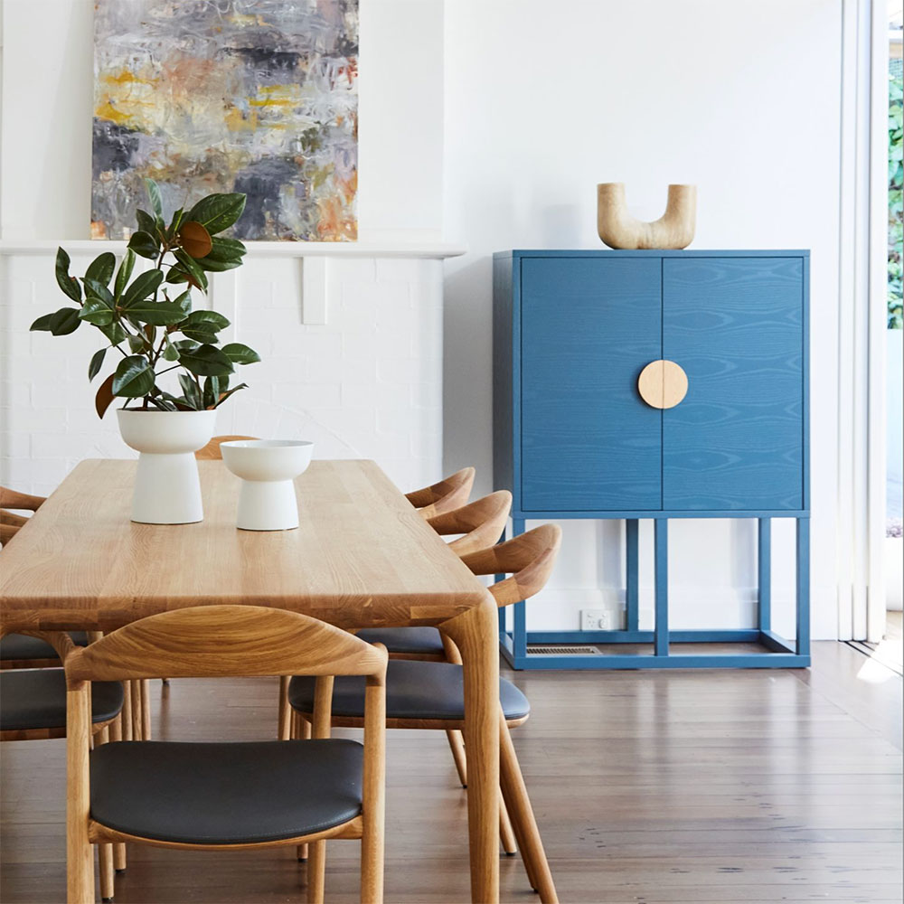 Dining room with timber table and blue cabinet by graduate Anna McMillan