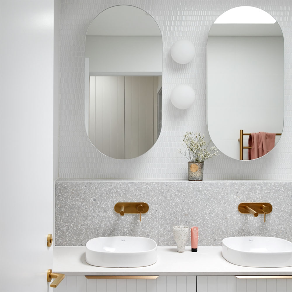 Bathroom with double basins and round mirrors by Anna McMillan