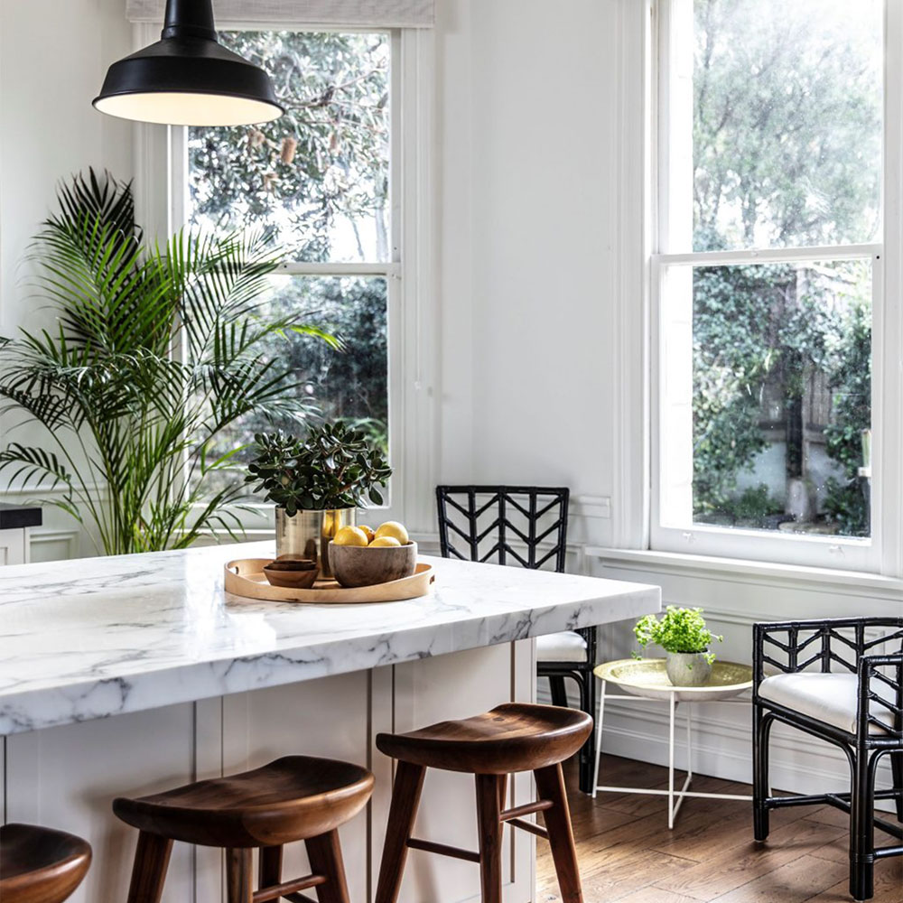 Bright kitchen with timber bar stools and indoor plants by Anna McMillan