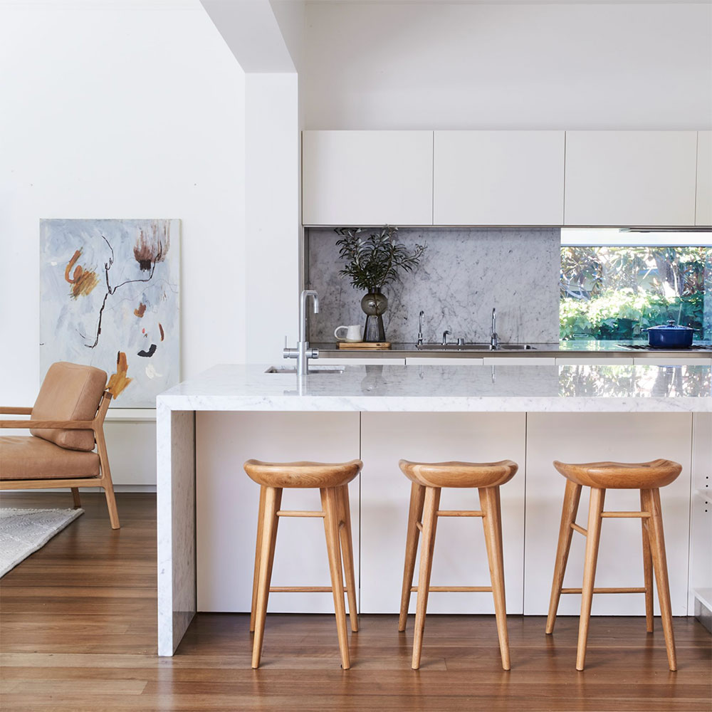 White kitchen island with timber stools by Anna McMillan