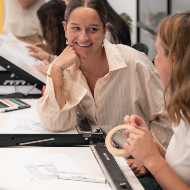 Interior design student smiling while working on a project in class