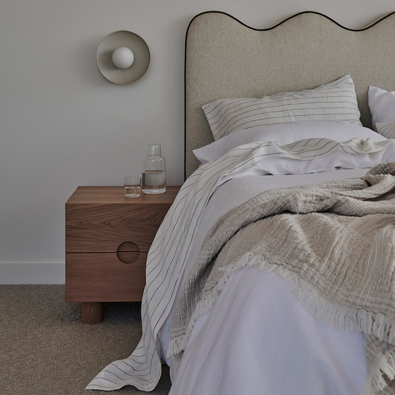 Fairhaven bedroom with a curved headboard and linen bedding by Rebecca Leijer