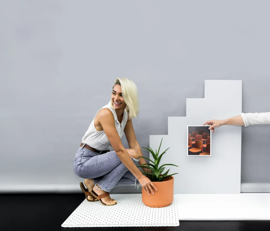 Styling student placing a potted plant on white plinths during a styled photo shoot